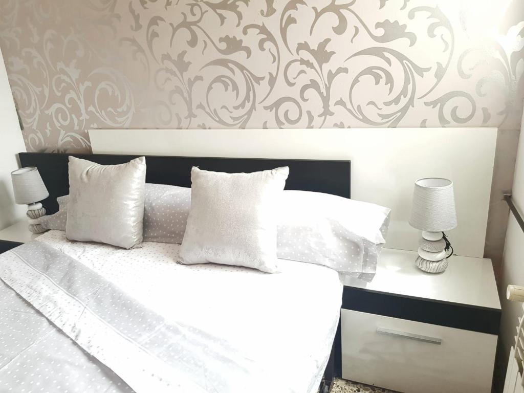 Schlafzimmer mit einem Bett mit weißer Bettwäsche und Kissen in der Unterkunft Piso de 3 habitaciones, 2 baños, calefacción, aire acondicionado y ascensor in Burriana