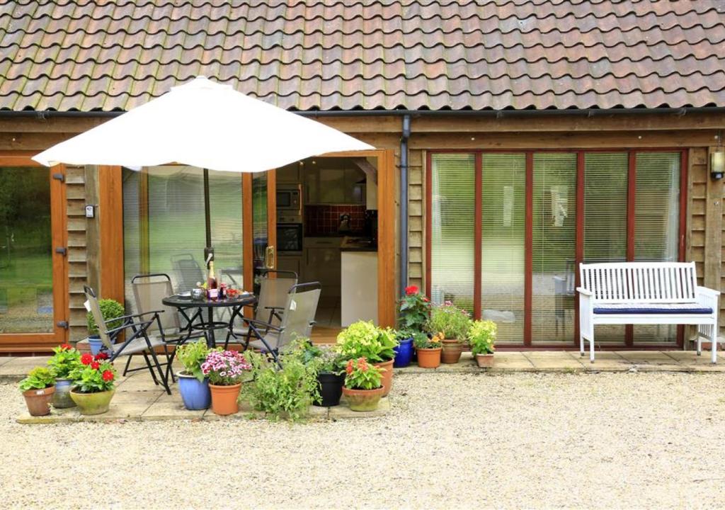 eine Terrasse mit einem weißen Regenschirm und Topfpflanzen in der Unterkunft Hawkeswade Barn in Ufford