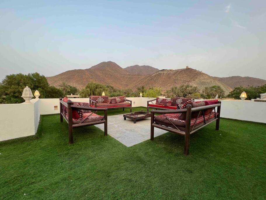 two benches on a lawn with mountains in the background at ALWADI Chalet - Khorfakkan in Khor Fakkan