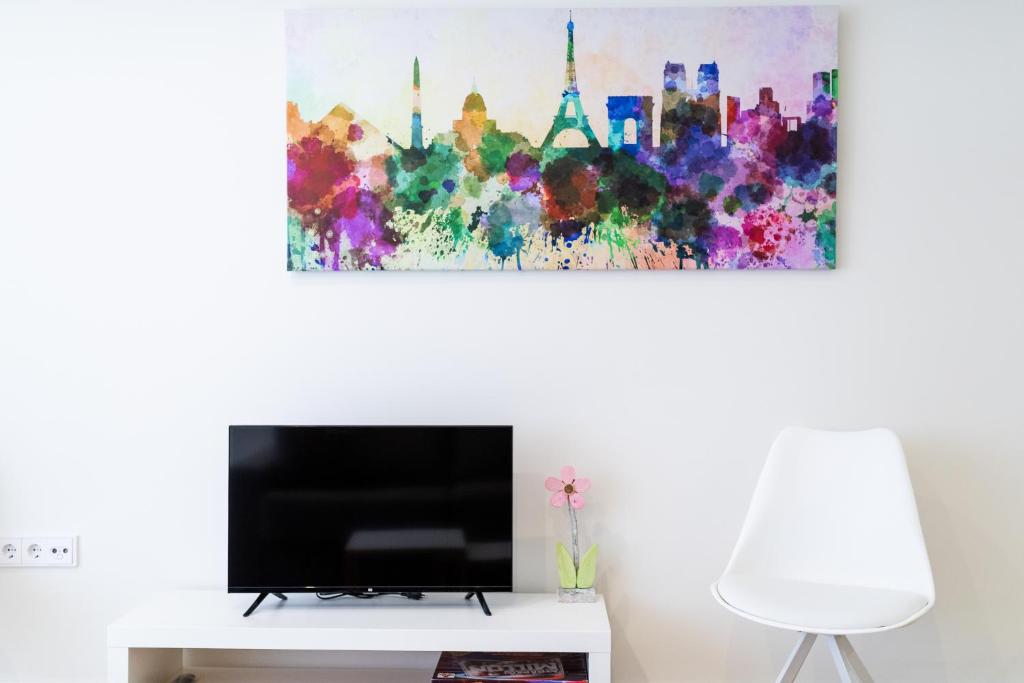 una sala de estar con TV y una pintura en la pared en Apart. en el centro de Granada, en Granada