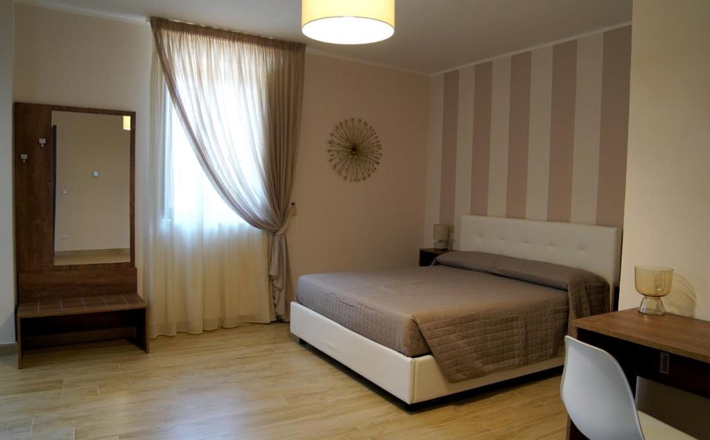1 dormitorio con cama, escritorio y espejo en B&B I Greci, en Vairano Patenora