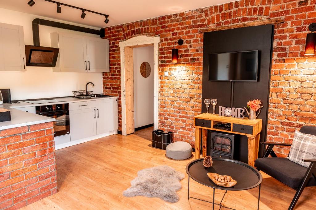 een keuken en een woonkamer met een bakstenen muur bij Apartamenty sudeckie nad zalewem III in Marczyce