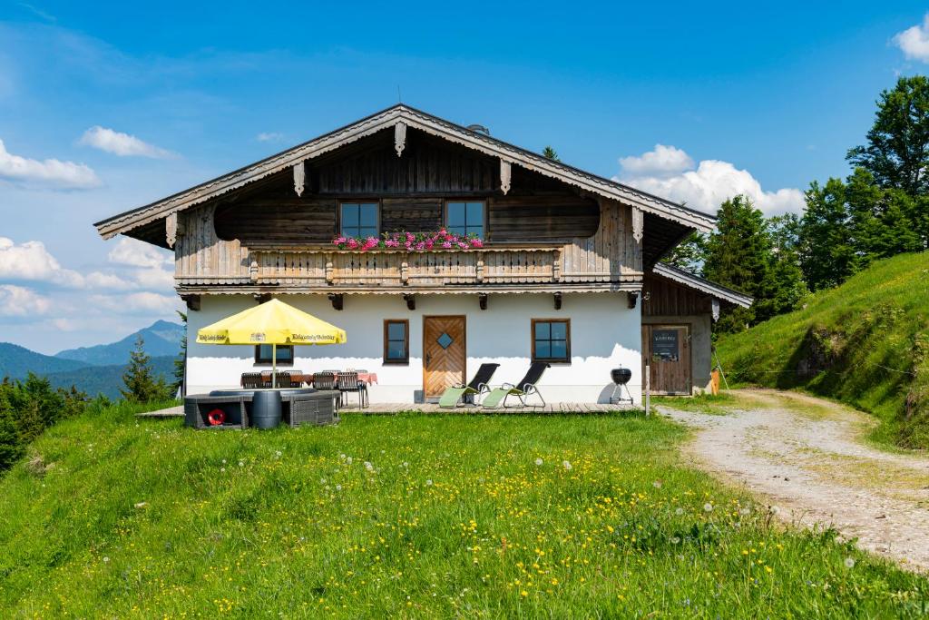 ein Haus auf einem Hügel mit einem Tisch und Stühlen in der Unterkunft Scheibenwald Hütte in Kössen