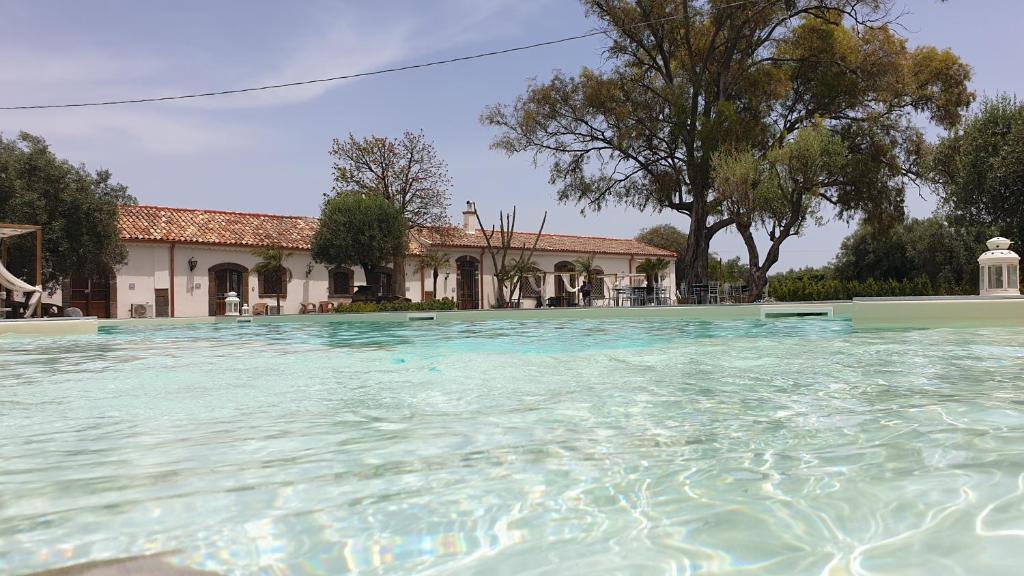 une grande piscine d'eau en face d'une maison dans l'établissement La Corte Della Regina, à Catane