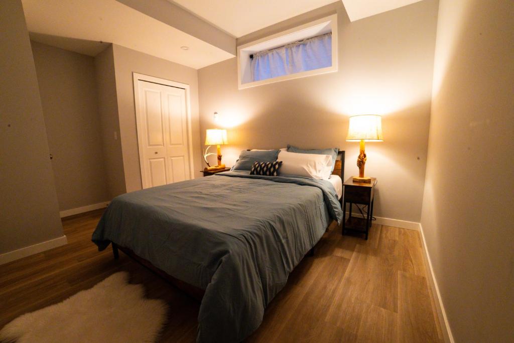 a bedroom with a bed and two lamps and a window at Kid & Pet Friendly Walkout BSMT 90 mins to Banff and 30 mins to Downtown Calgary in Calgary