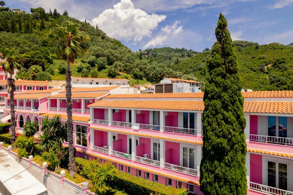 une rangée de bâtiments roses avec des palmiers dans l'établissement Pink Palace Beach Resort, à Agios Gordios