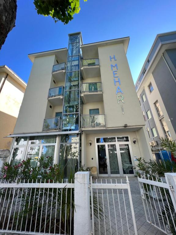 a building with a white fence in front of it at Mehari Hotel Rimini in Rimini