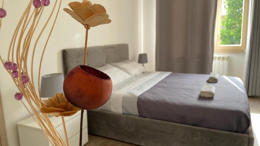 ein Schlafzimmer mit einem Bett und einer Vase mit einer Blume in der Unterkunft Lux Kuoni Grace - Appartamento a due passi dal porto in Civitavecchia
