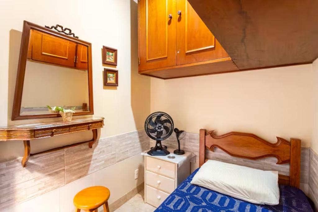 a small bedroom with a bed and a mirror at Quarto em casa de vila em Botafogo, Rio de Janeiro in Rio de Janeiro