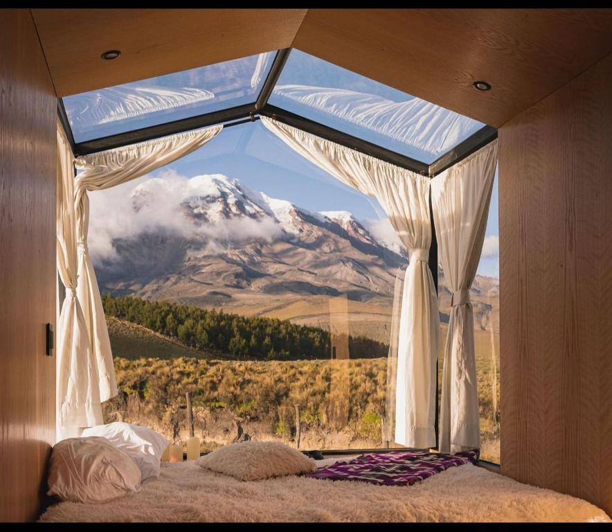 a bedroom with a large window with a mountain view at Nomads Ecuador in Chimborazo