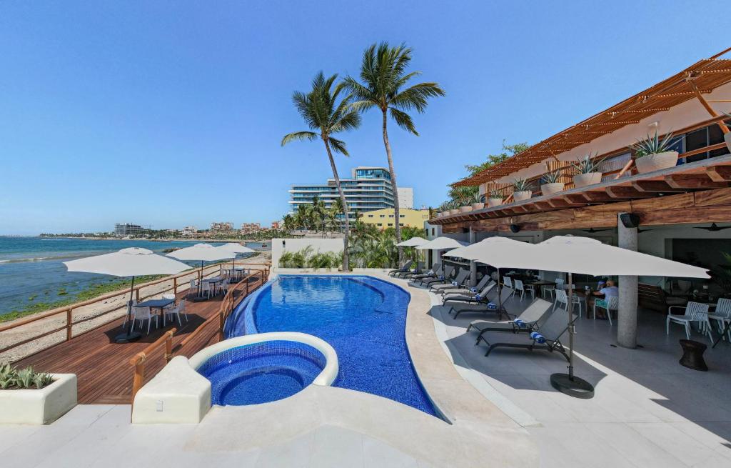 - une piscine avec chaises longues et parasols et l'océan dans l'établissement Hotel Ysuri Bucerias, à Bucerías