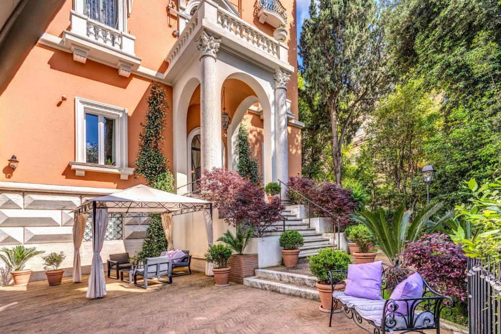a house with a patio with chairs and an umbrella at Mangili Garden Hotel in Rome