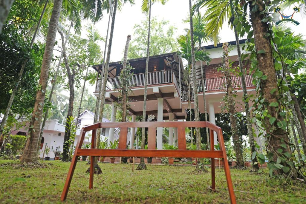 um banco de madeira em frente a uma casa em Serenity Villa and Treehouse em Palakkad