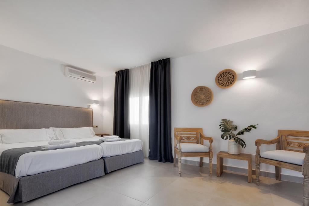 a bedroom with a large bed and two chairs at Alojamientos Turísticos Cardona - Estudio Doble Superior in Es Pujols