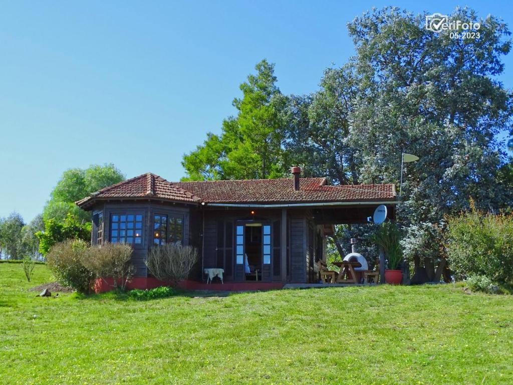 una pequeña casa en una colina con un campo de hierba en Casa de campo la serena en Minas