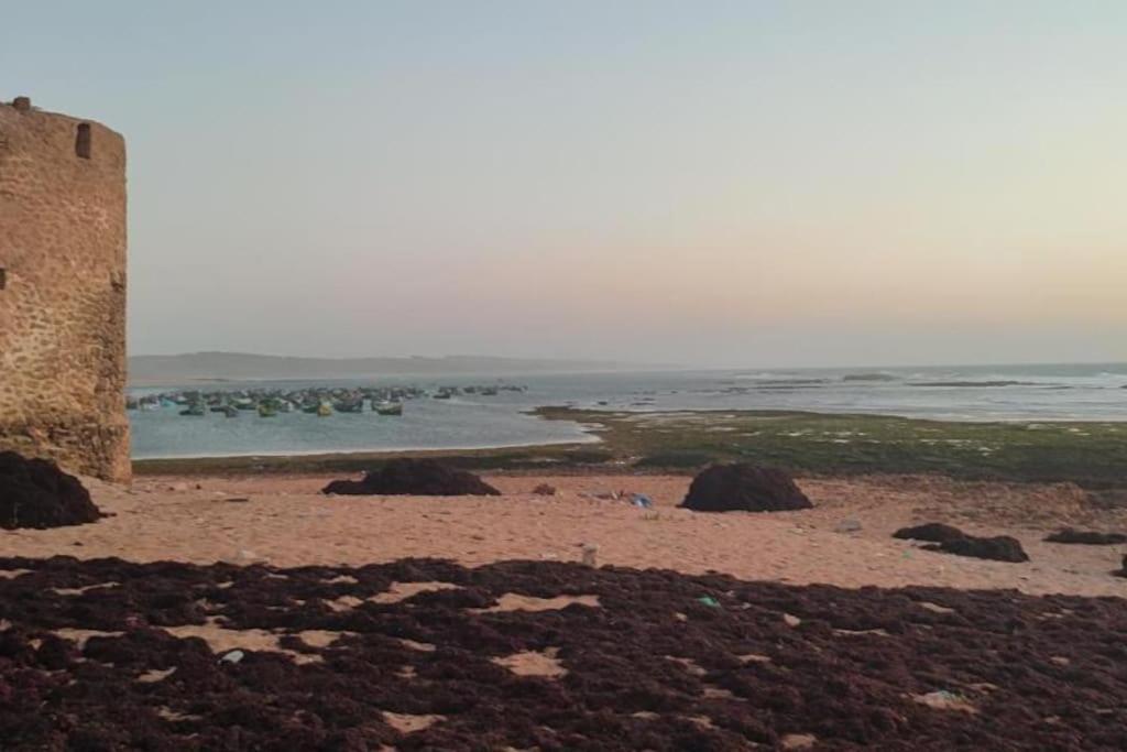 um edifício numa praia com o oceano ao fundo em Villa Mama Swiriya Atlantique em Souira Guedima