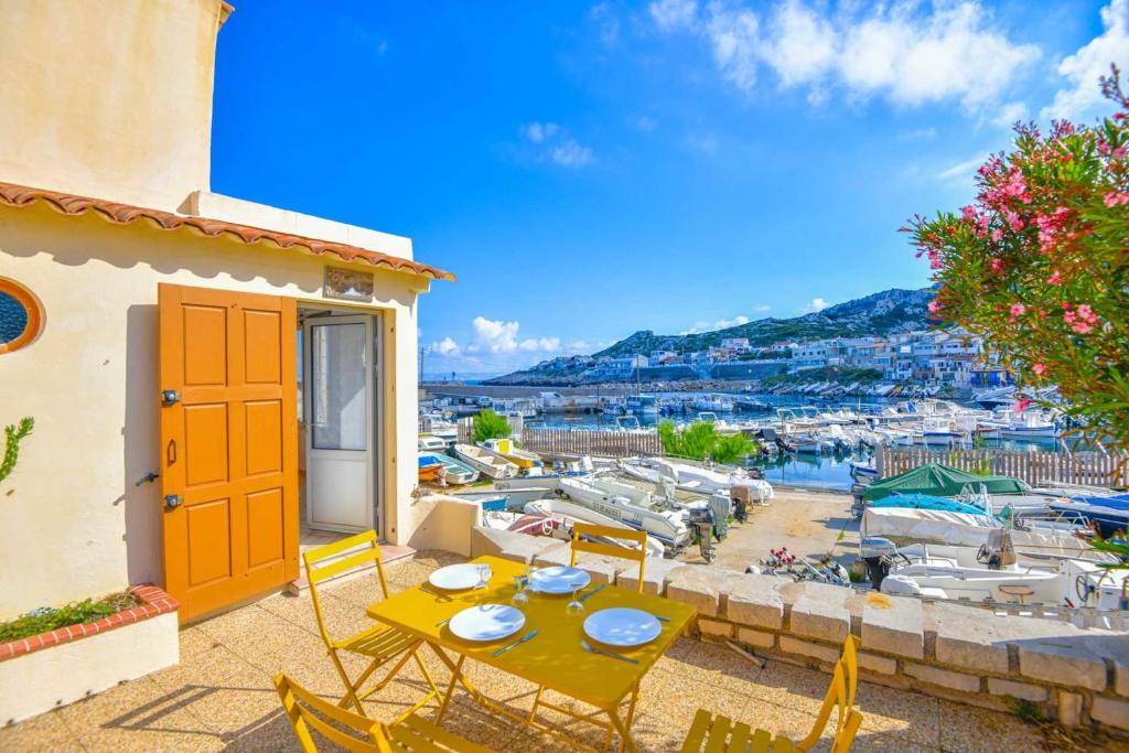 un patio con una mesa y sillas y un puerto deportivo en Le Cabanon des Goudes - Vue mer et parking en Marsella