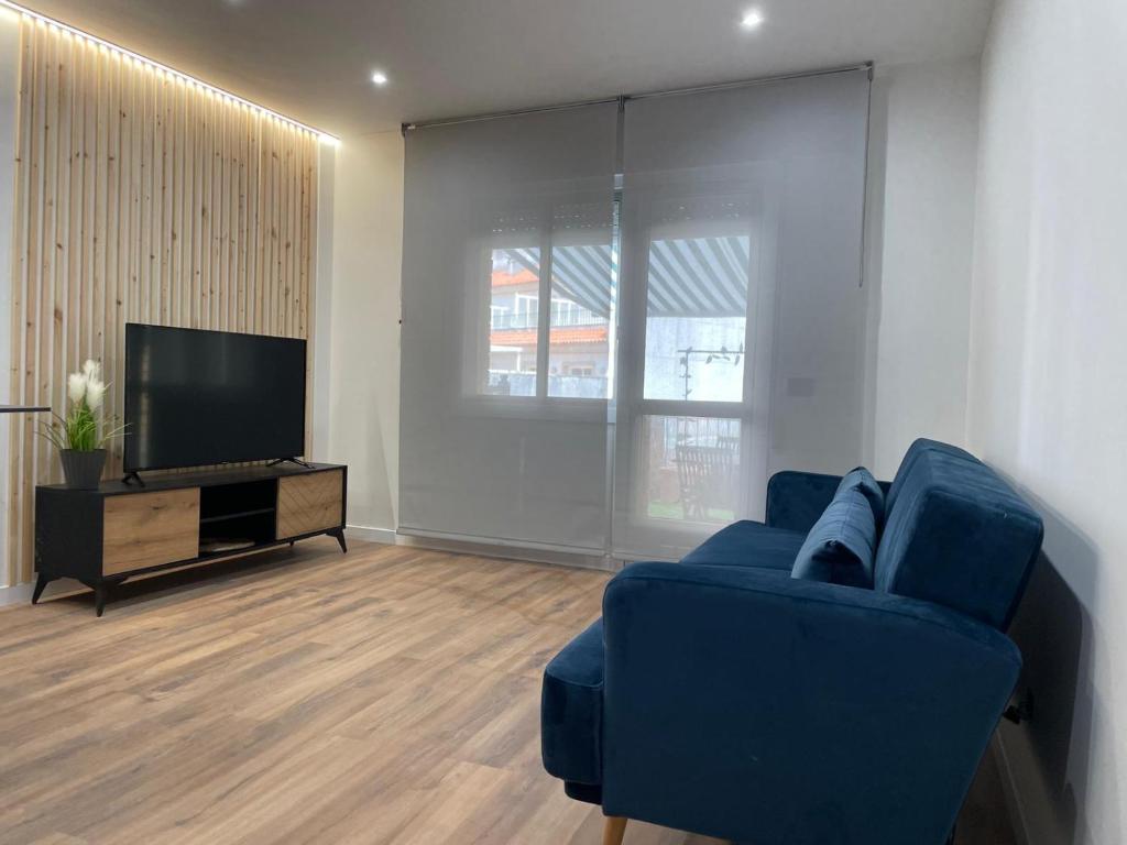 sala de estar con sofá azul y TV de pantalla plana en Apartamentos JL&DN Primera Línea Playa Silgar *Sansenxo*, en Sanxenxo