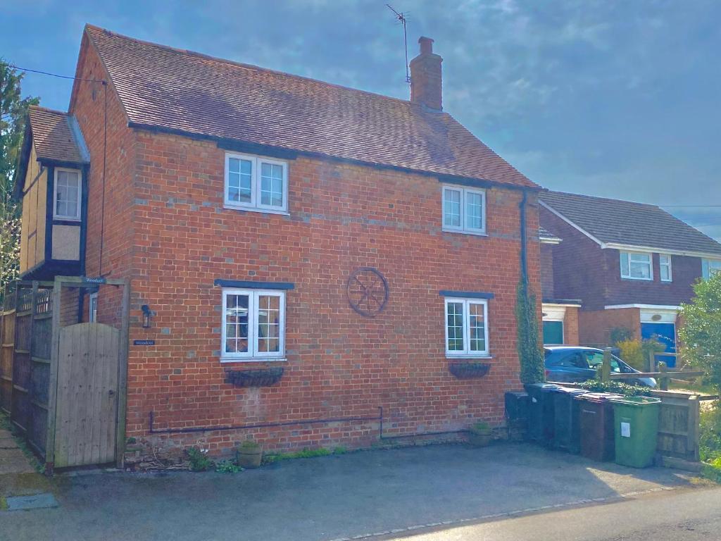 een rood bakstenen huis met een hek ervoor bij Private Bedrooms in Quaint Oxfordshire Village Cottage in Wantage