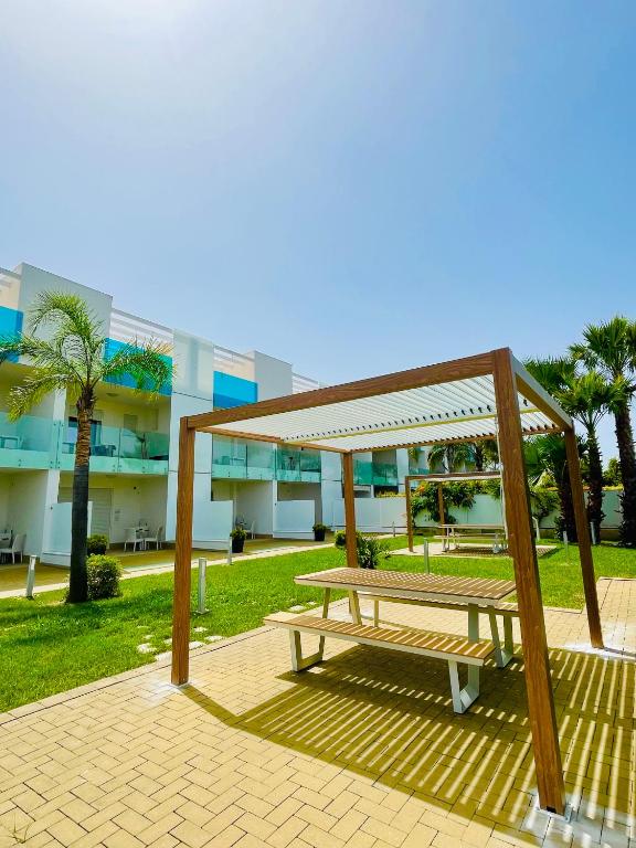 a wooden bench sitting in front of a building at Vespucci Apartments Torre Lapillo in Torre Lapillo
