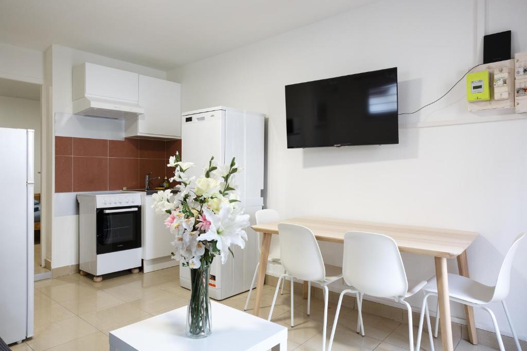 uma cozinha com uma mesa com cadeiras brancas e um vaso de flores em F2 Osakue em Aubervilliers