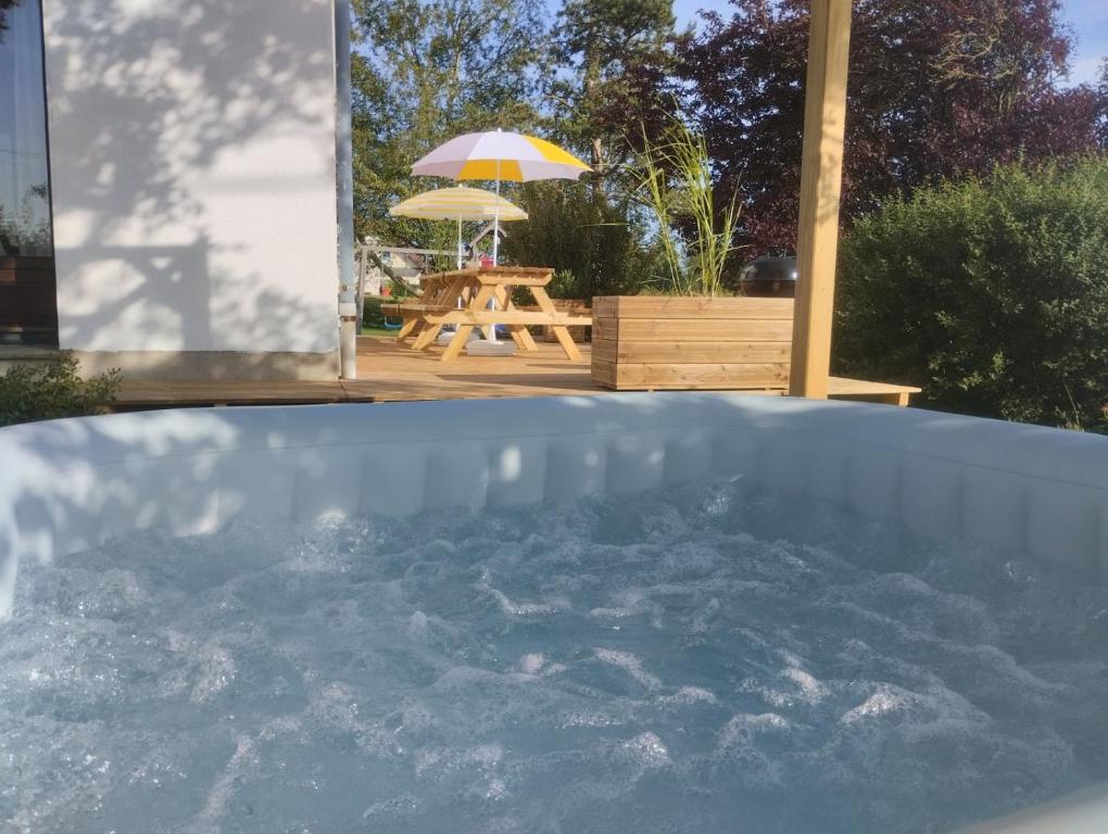 a pool of water with a picnic table and an umbrella at Maison de campagne avec jacuzzi 