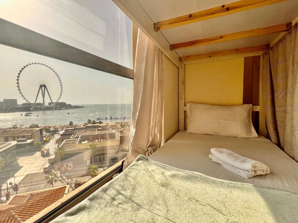 a bed in a room with a view of the beach at York Backpackers - Jumeirah Beach in Dubai