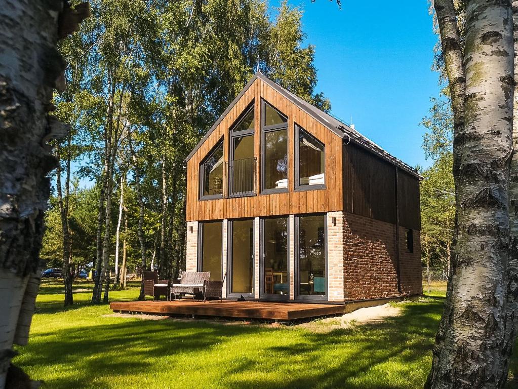 a house with large glass windows on a lawn at Słowińskie Tarasy in Smołdziński Las