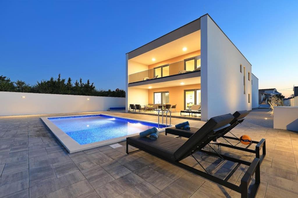 ein Haus mit einem Pool und einer Chaiselongue in der Unterkunft Villa Good Vibes with heated pool in Vrsi