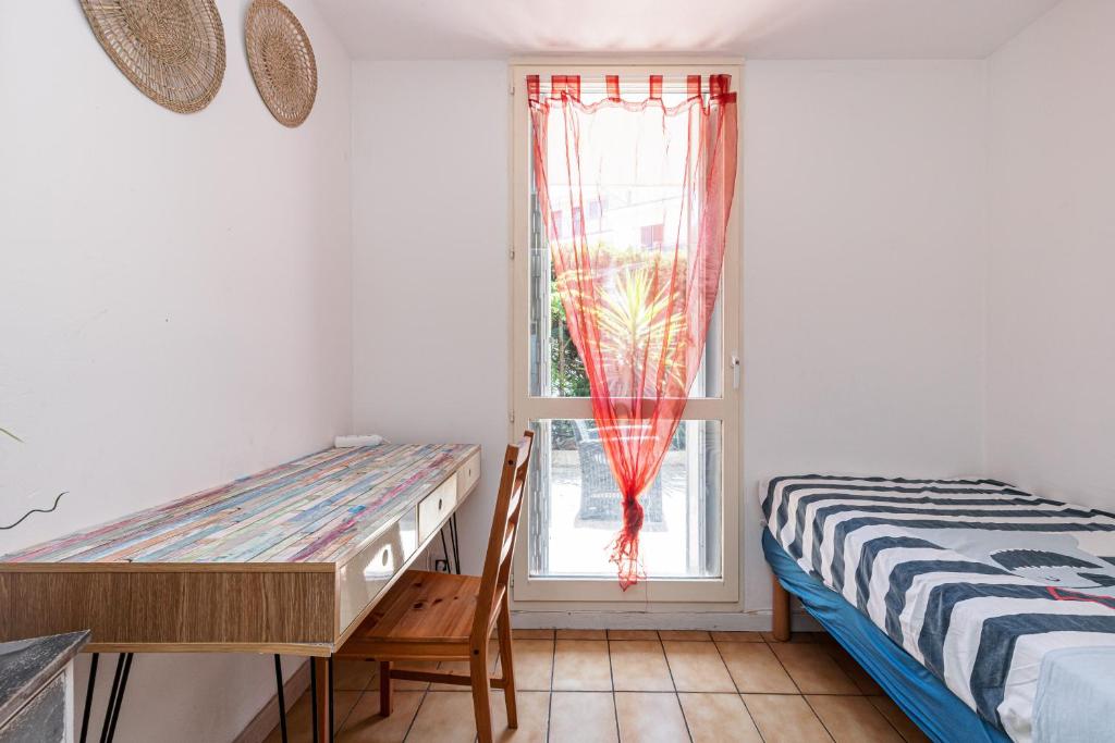 a bedroom with a bed and a desk and a window at Appartement familial avec jardin ensoleillé dans la cité des Potiers in Vallauris
