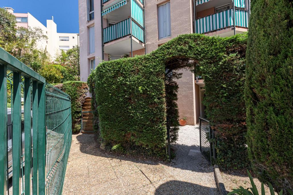 an ivy covered fence in front of a building at Appartement familial avec jardin ensoleillé dans la cité des Potiers in Vallauris