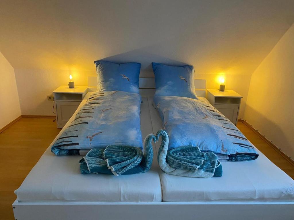 a white bed with blue pillows and towels on it at Zaunkönigin in Norden