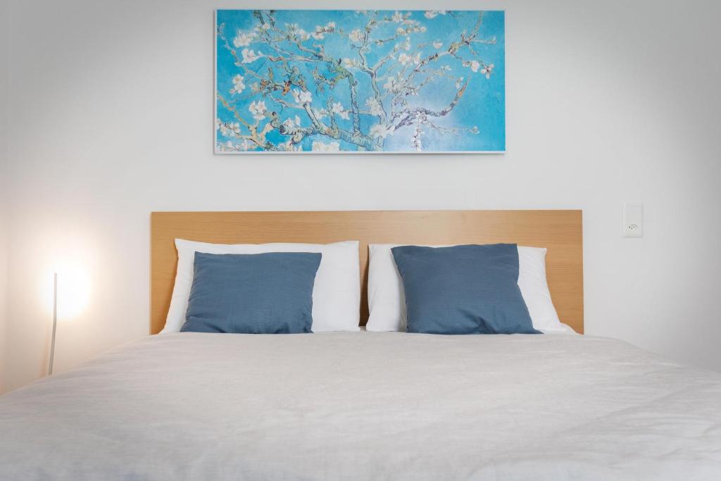 Una cama con almohadas azules y una pintura encima. en Easy flat Vezia, indipendent entrance, free parking, en Lugano