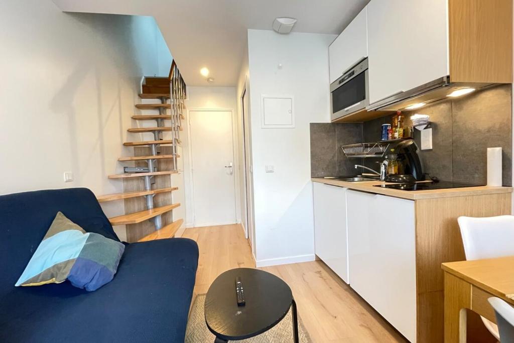 uma pequena sala de estar com um sofá azul e uma cozinha em Coeur Massy M7 Rer BC 600m - Orly20 min em Massy