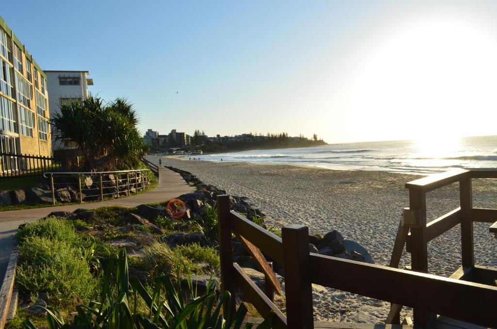 a beach with a fence and the ocean at Pandanus Shores Kings Beach in Caloundra