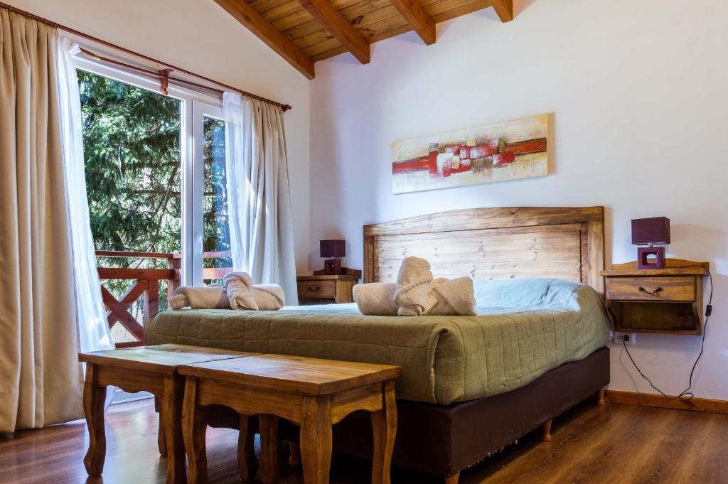 1 dormitorio con cama, mesa y ventana en BOG Apart Foresta - A minutos del cerro bayo en Villa La Angostura