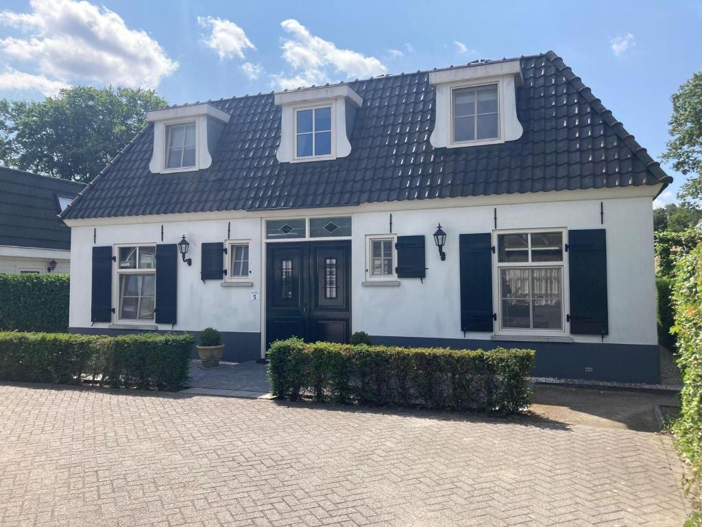 een wit huis met een zwart dak bij Great holiday home with a heated pool in Kaatsheuvel