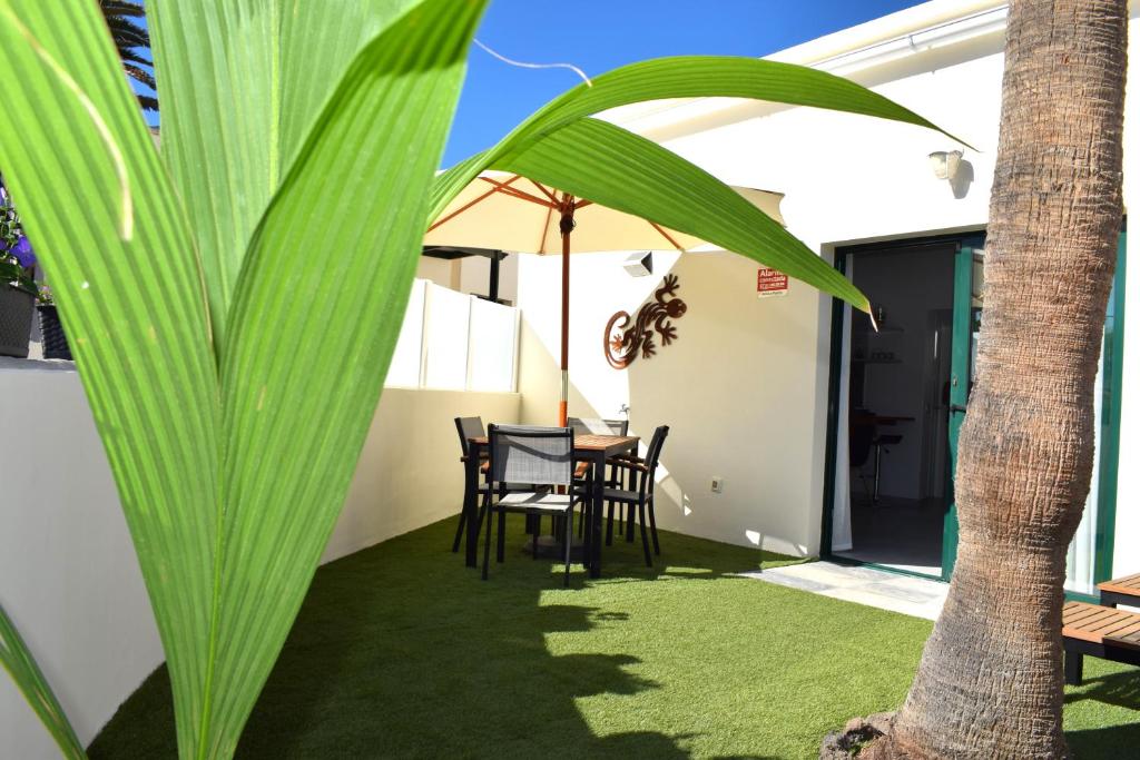 een patio met een tafel en stoelen en een palmboom bij Bungalow La Palmera - 2 bedroom - PLAYA ROCA residence sea front access - Pool View - Free AC - Wifi in Costa Teguise