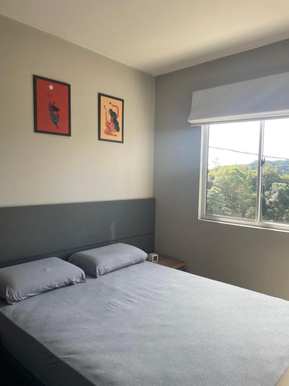 a bedroom with a bed with two pillows and a window at Apto com linda vista in Campo Largo