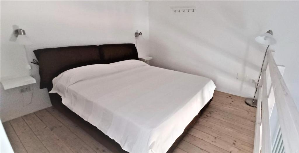una camera da letto con un letto con lenzuola bianche e una lampada di Casa di Marco a Lecce