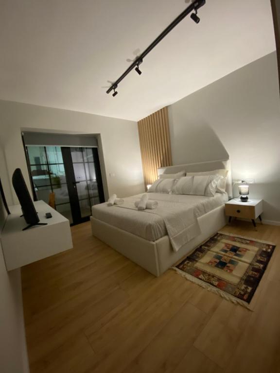 - une grande chambre blanche avec un lit et une télévision dans l'établissement Lucas Downtown, à Tirana