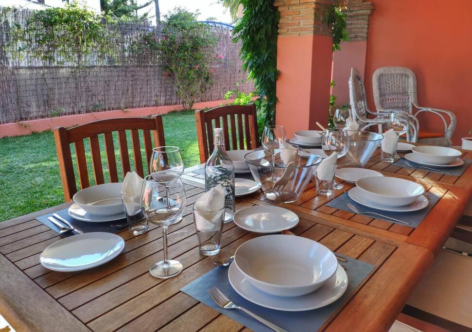a wooden table with plates and wine glasses on it at Villa privada en la playa 8 personas in Marbella