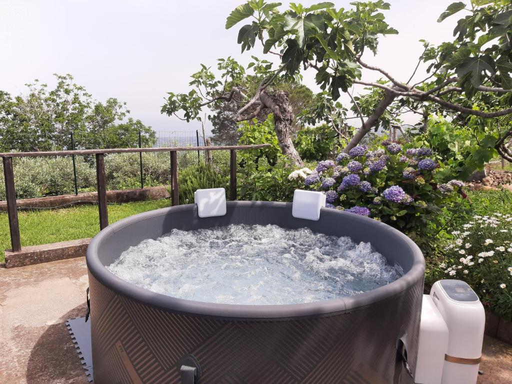 una bañera de hidromasaje en un patio con flores en Casa Leopina Apri gli occhi e vola oltre il mare en SantʼAlfio