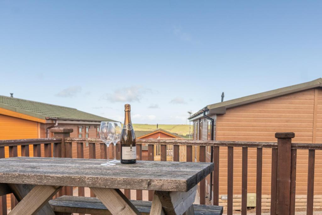 a bottle of wine on a wooden table with a wine glass at 56 Meadow View in Woolacombe