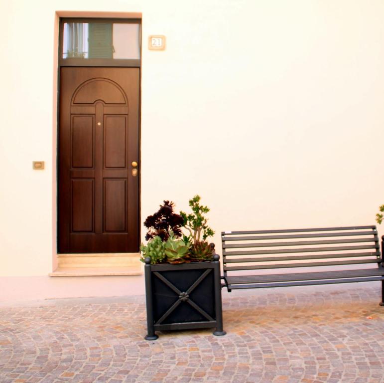 un banc devant une porte avec une plante en pot dans l'établissement Casetta Monet - nel cuore della pedonale, à Dolceacqua