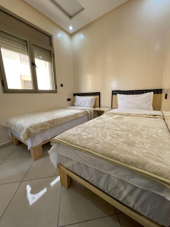 two beds in a room with two windows at hôtel Bahnini in Dakhla