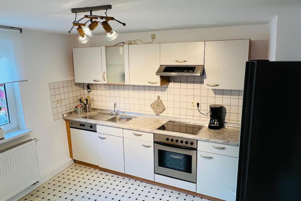 una cucina con armadi bianchi e piano cottura di Mitten in den Weinbergen a Sommerhausen