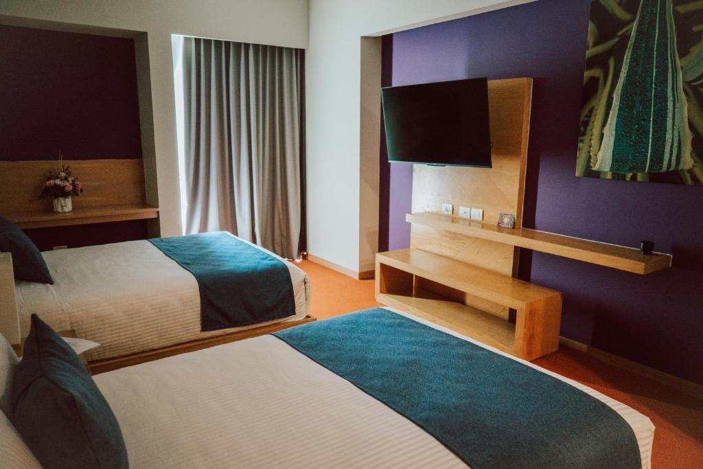 Habitación de hotel con 2 camas y TV de pantalla plana. en Gran Hotel Concordia en Irapuato