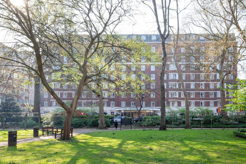 a park with trees and a building in the background at Tavistock Hotel in London