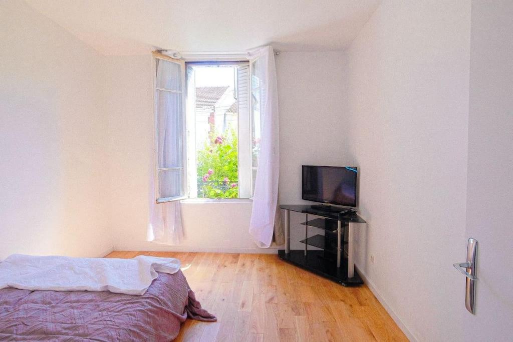 a bedroom with a bed and a television and a window at Résidence de Rose, Bas, La Courneuve in La Courneuve